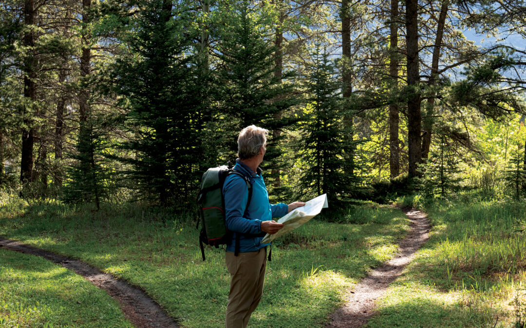 Man hiking in forest looking at map deciding which path to take